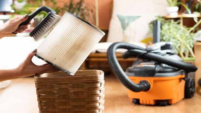 خانمی در حال تمیز کردن فیلتر جاروبرقی با فرچه است